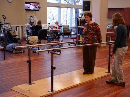 An elderly woman is strengthening her walk in the physical therapy treatment room